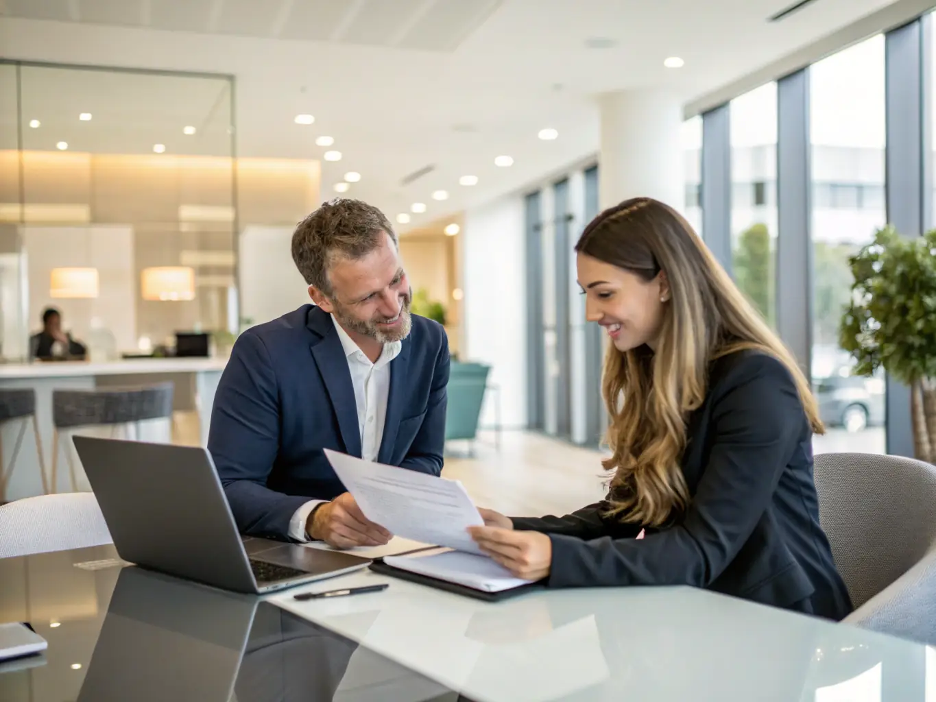 An HR professional reviewing policy documents with a client in a modern office, representing HR Compliance & Policy Development services.
